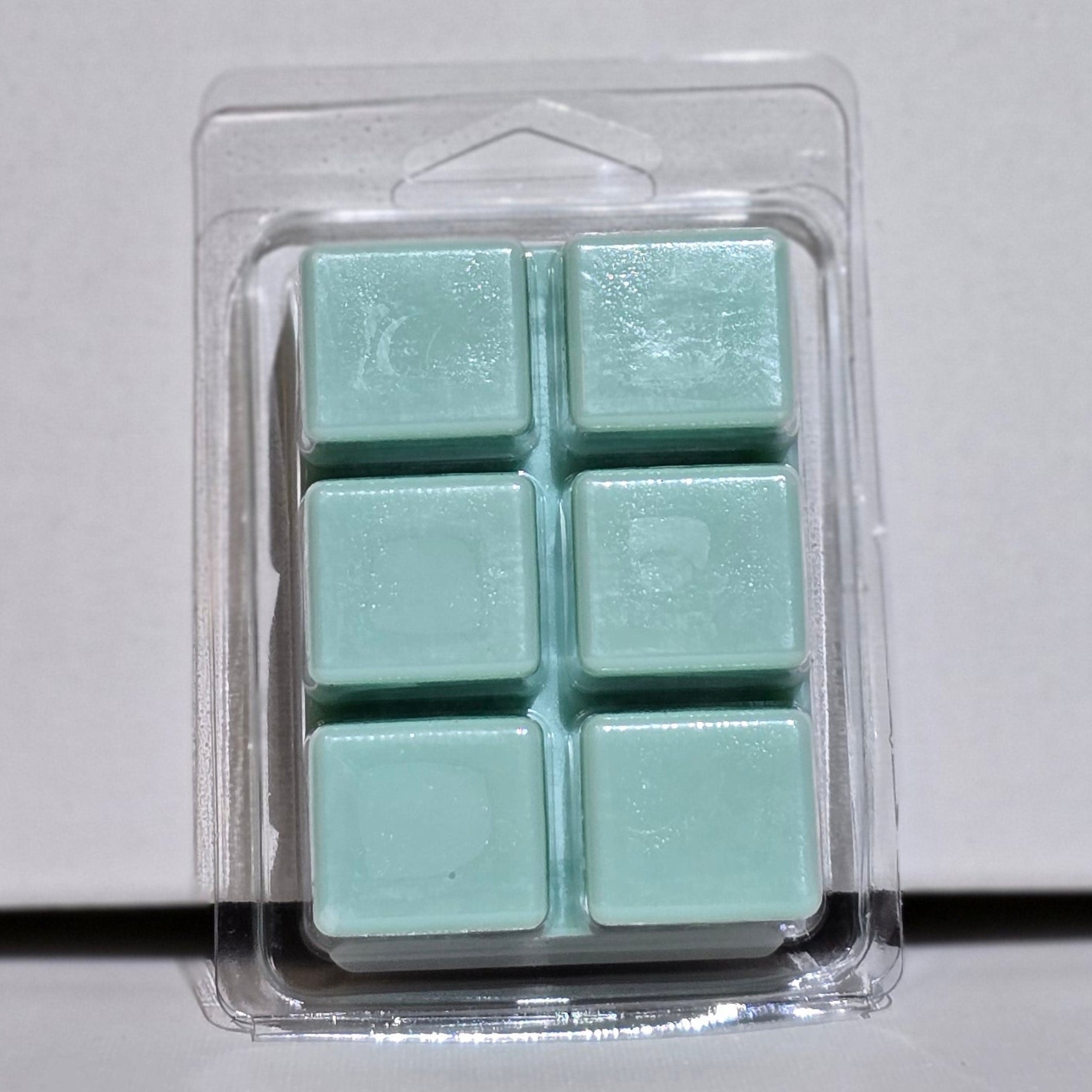 Packaged teal wax melts on a light gray background