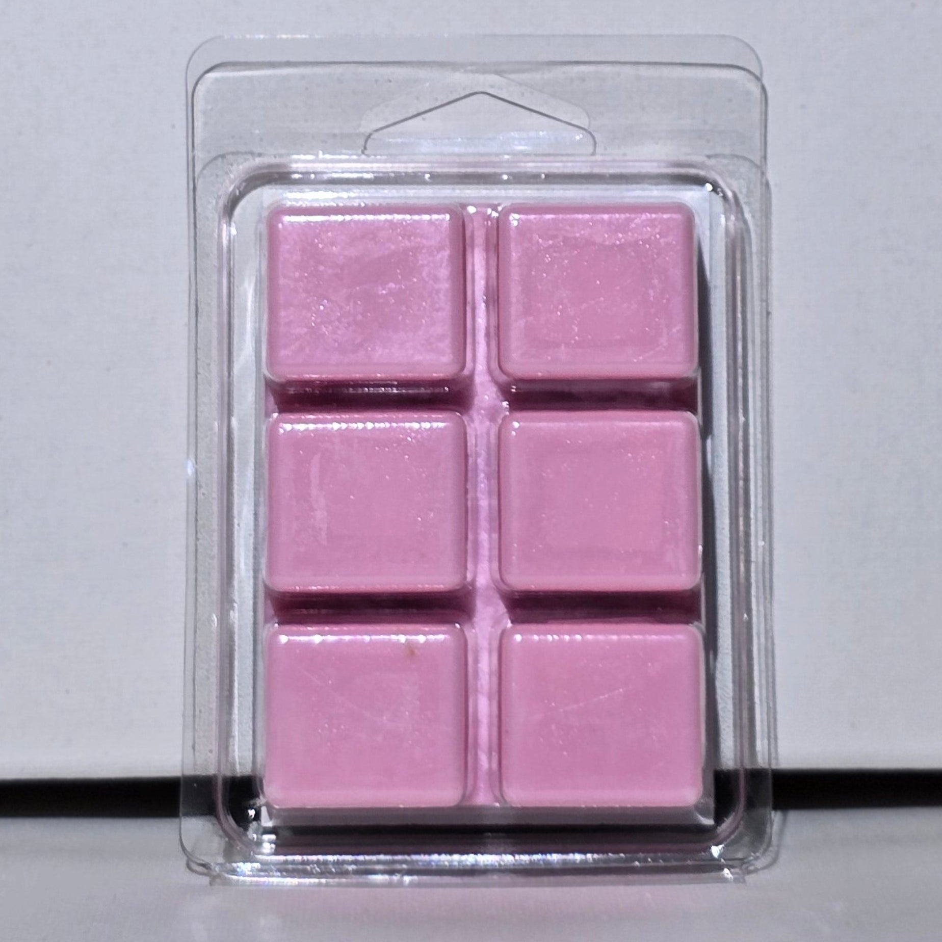 Pink wax melts in a clear plastic packaging on a light gray background