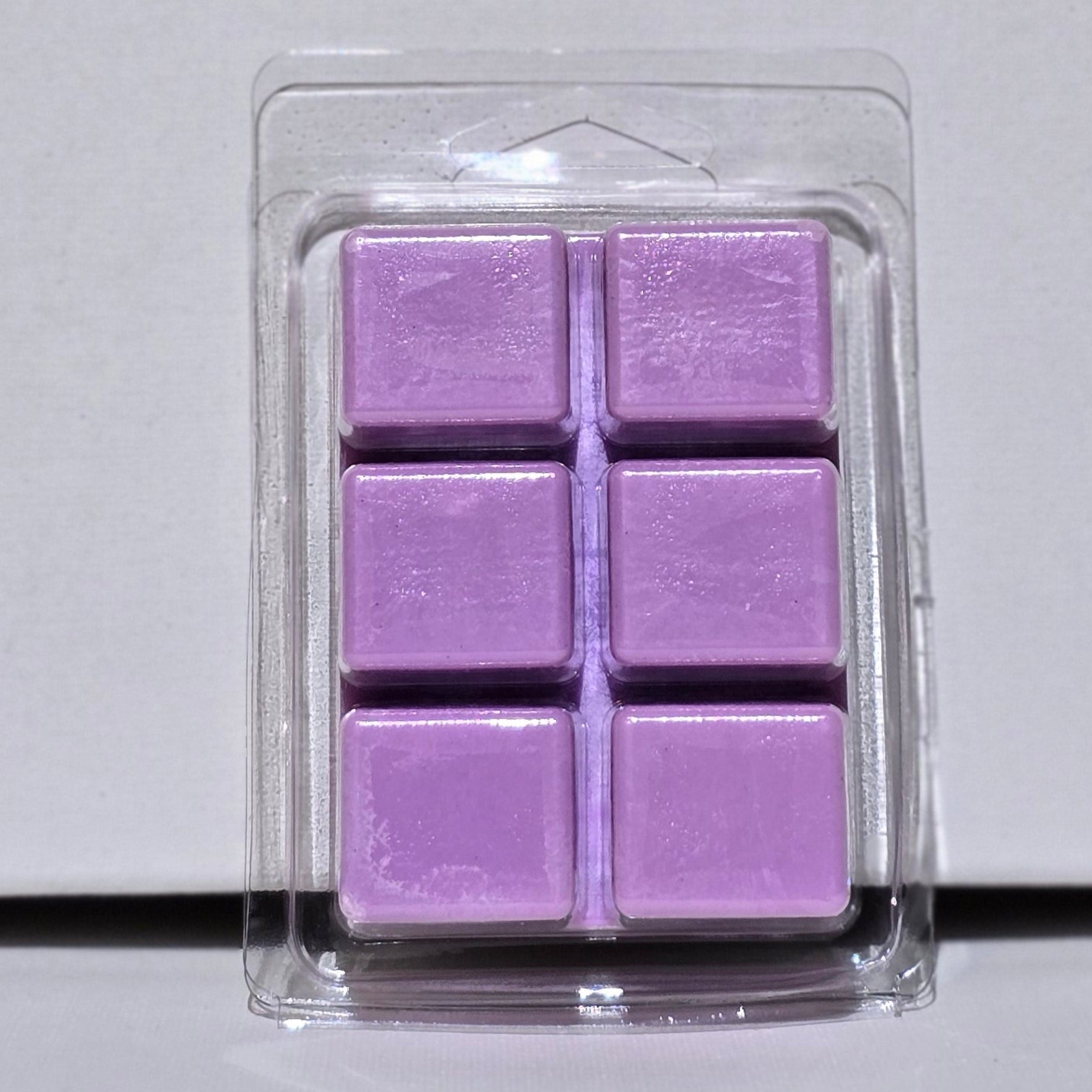 Purple wax melts in a clear packaging on a light gray background